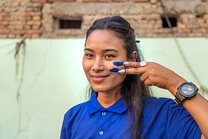 A woman draws an equals sign on her cheek.